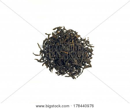 Still Life with a pile of black Assam tea leaves scattered on a table isolated on white background