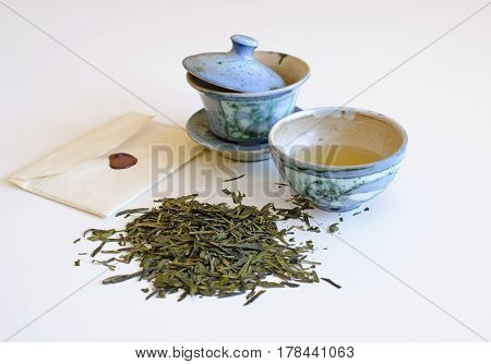 Cup of tea with tea leaves and scattered pile, isolated on a white background