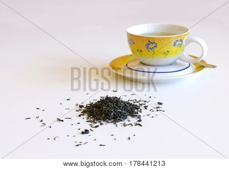 Cup of tea with tea leaves and scattered pile isolated on a white background
