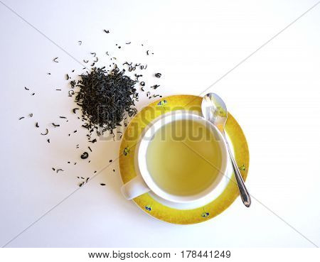 Cup of tea with tea leaves and scattered pile isolated on a white background