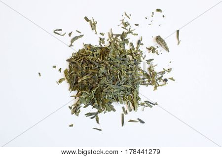 Still Life with a pile of green tea leaves scattered on a table isolated on white background