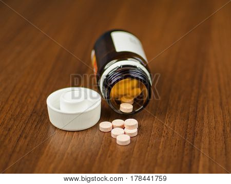 View of glass with pills lying on a wooden background