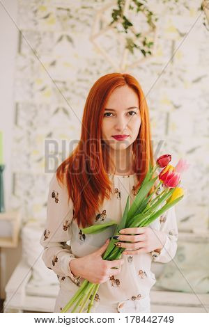 red-haired girl holding a bouquet of tulips