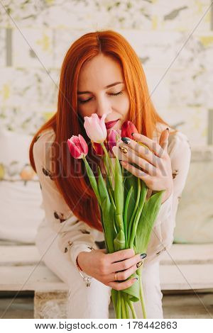 red-haired girl sniffing a bouquet of tulips