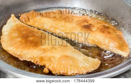Patties with meat frying in oil in frying pan.