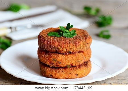 Homemade carrot cutlets on a plate. Delicious fried carrot cutlets with green onions and parsley. Healthy meatless cutlets recipe. Closeup