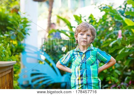 little blond preschool kid boy discovering flowers and butterflies at botanic garden. schoolchild interested in biology. active educational leisure with kids in museum.