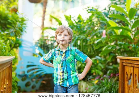 little blond preschool kid boy discovering flowers and butterflies at botanic garden. schoolchild interested in biology. active educational leisure with kids in museum.