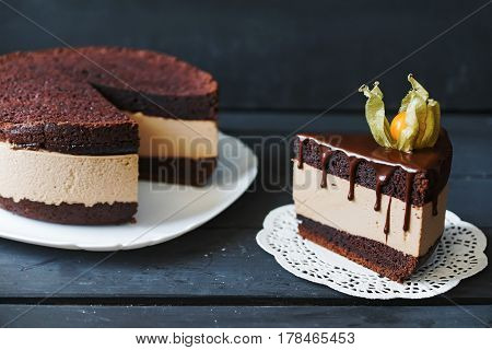 Delicious cake with chocolate sauce, fruit and plate with slace of this cake on lace napkin