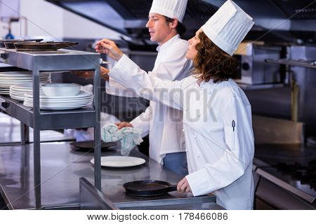 Two chefs working at order station in a restaurant kitchen
