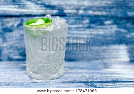 Transparent glass with tonic with ice and lime on a blue denim background