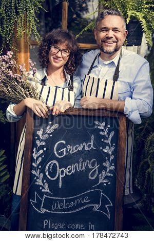 Adult Man and Woman Standing with Grand Opening Sign