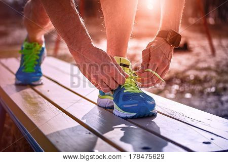 Athlete during training tying shoelaces on sneakers summer.