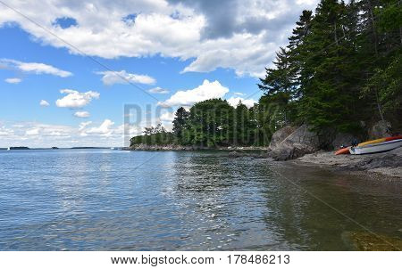 Kayak and row boat on the shore of a rocky beach in Casco Bay Maine.