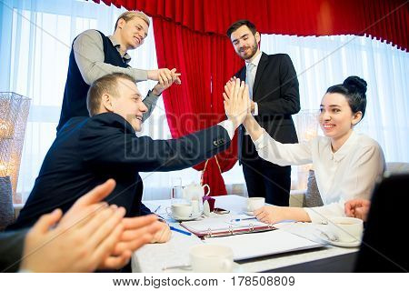 Two businessmen are highfiving each other while their partners shake hands