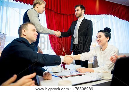 Two businessmen are highfiving each other while their partners shake hands