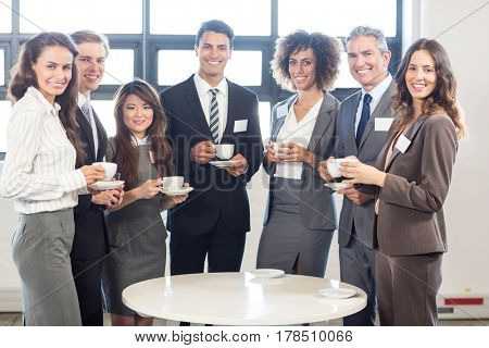 Portrait of businesspeople standing together and smiling in office during breaktime