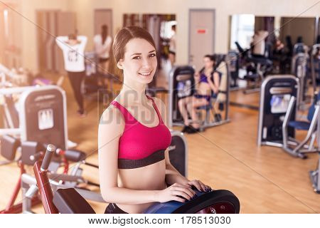 Young woman doing workout on exercise machine in gym