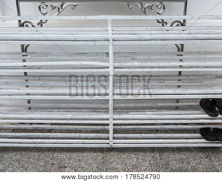 Old metal shoe rack with the black slippers in the Thail temple.