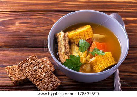 Puchero Soup With Corn And Parsley On Wooden Table