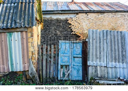 Exteriour of abandoned obsolete rustic house with damaged brick wall and blue door