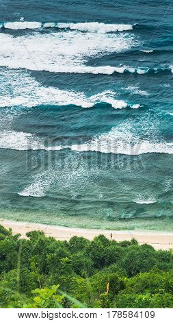 Waves Cascade and Man looking into Element on Nunggalan Beach. Uluwatu, Bali, Indonesia.