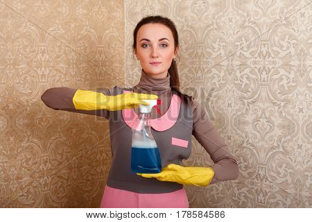 Young woman in rubber gloves shows spray