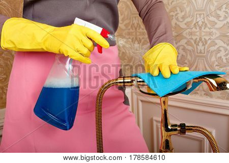 Female hands in rubber gloves cleans bathroom