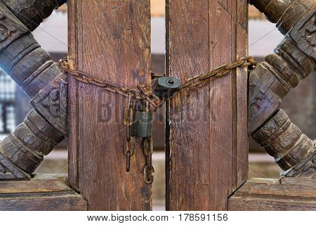 Old rusted padlocks and rusted chain on a half closed wooden interleaved double door