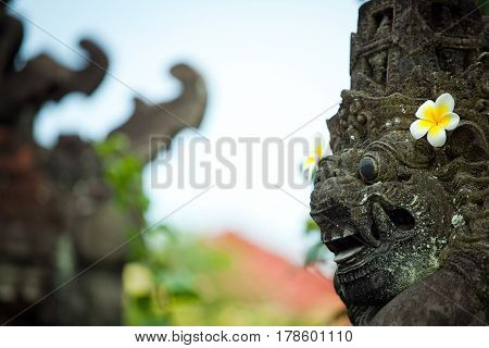 Traditional statue of Bali with flowers of plumeria