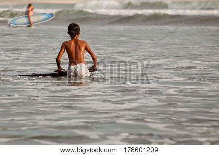 Boy surfer trying to catch a wave on the sea