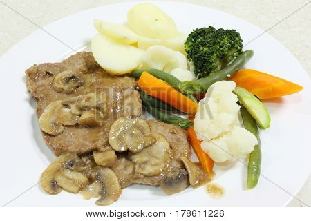 Roast beef with a mushroom gravy, served with boiled potatoes and steamed vegetables.