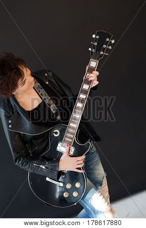 girl with short hair in leather jacket with a guitar