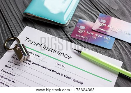 Travel insurance application form with credit cards and passport on gray wooden desk background