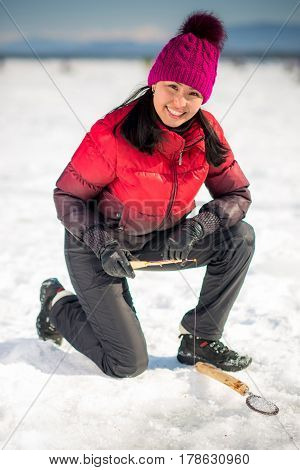 Woman ice-fishing in the winter on the lake