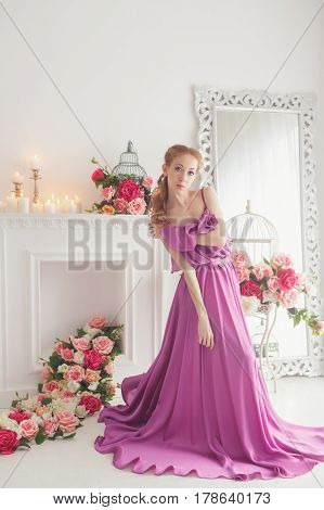 Lovely girl in beautiful dress posing in studio. Spring flowers and a romantic mood.