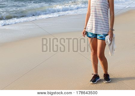 A young woman wipes the sweat with a towel after jogging on the beach
