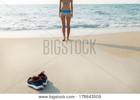 After training young woman left sneakers on the beach and went swimming