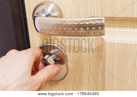 The man's hand closes the lock on the door. Turn the door latch. The concept of home security. Close all doors to the lock.