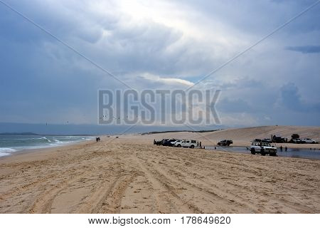 Horizontal landscape of the beach with cars. 4wd cars at Crokers creek (Belmont - Nine Miles - Beach NSW Australia). Redhead Point in the background.