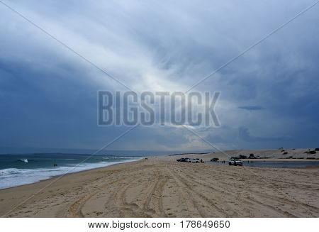 Horizontal landscape of the beach with cars. 4wd cars at Crokers creek (Belmont - Nine Miles - Beach NSW Australia). Redhead Point in the background.