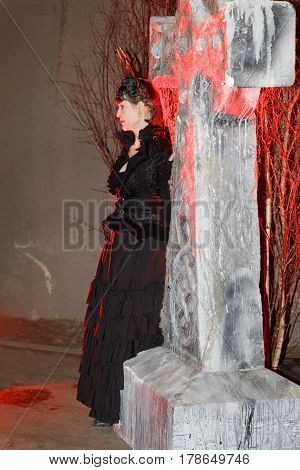 STOCKHOLM SWEDEN - MAR 25 2017: Woman in black dress looking like a vampire in red light leaning on a tomb stone in the Stockholm Tunnel Run in the Stockholm Tunnel Run Citybanan 2017. March 25 2017 in Stockholm Sweden