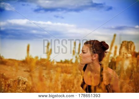 The girl in the golden grass on vone blue sky and clouds