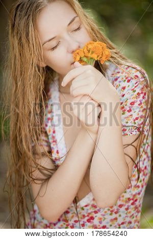 beautiful  blond girl smelling flowers in nature