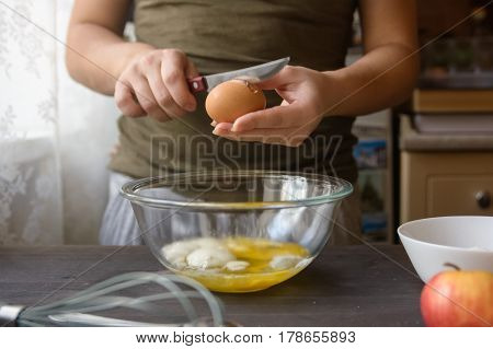 Close-up of woman's hands breaking egg during cooking