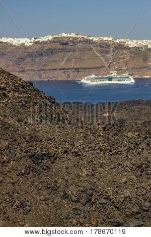 Volcano crater with a distant view of the city of Fira Santorini and a cruise.