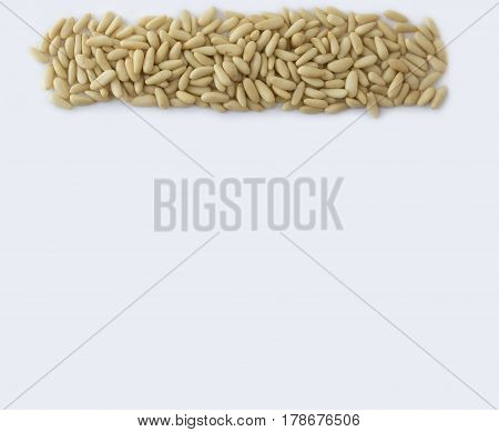 Pine nuts at border of image with copy space for text. Kernels nuts on a white background. Top view. Vegetarian or healthy eating. Background of pine nuts