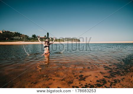 Woman splashing out water with the hands at the beach in Australia.