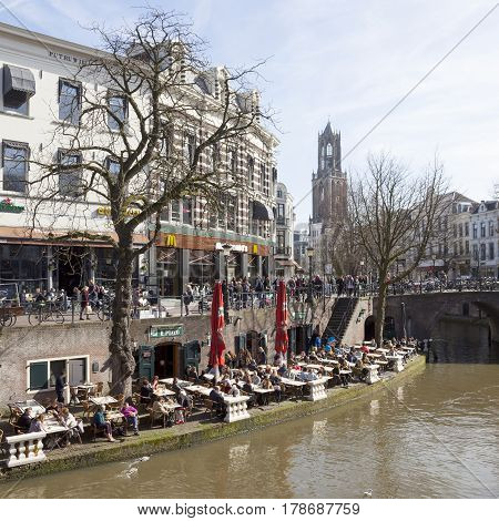 utrecht netherlands 15 march 2017: people enjoy sunny day in early spring on open air cafe at oude gracht in utrecht with Dom tower in the background