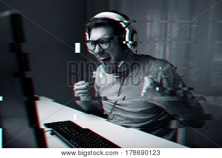 technology, entertainment and people concept - happy young man in eyeglasses with headset playing and winning computer game at home and streaming playthrough or walkthrough video, glitch effect